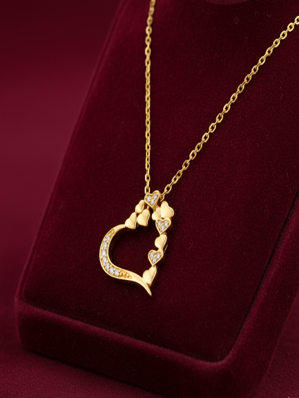 Gold heart-shaped necklace with floral design on a red velvet background