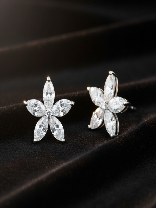 Flower-shaped silver earrings with clear gemstones on a dark background